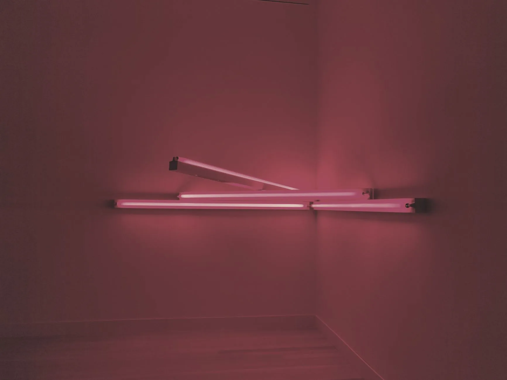 Person arranging abstract installation in large, dimly lit room, avant-garde movements shaping installation art.