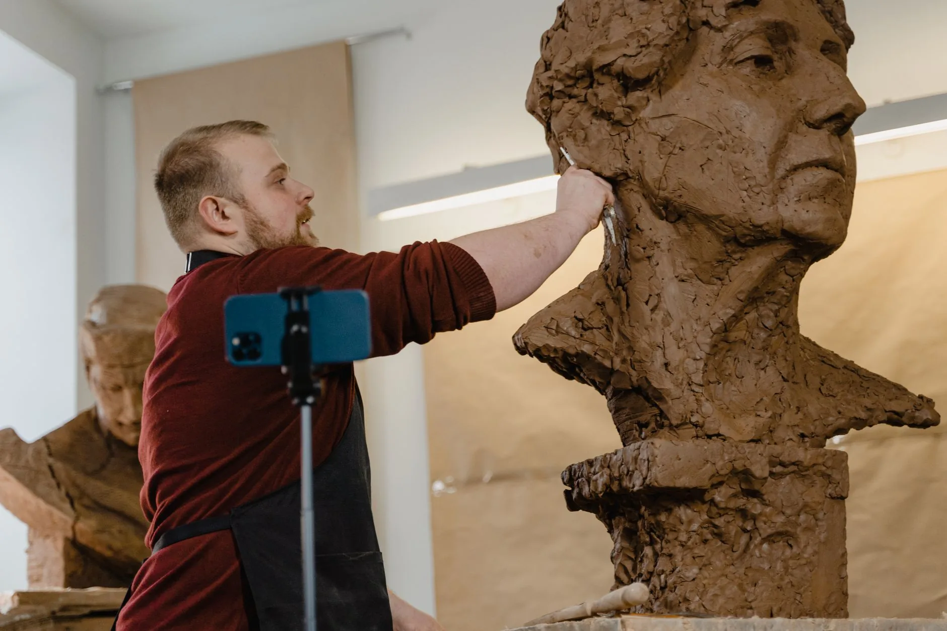 A person molding clay in a softly lit art studio, showcasing artistic mediums.