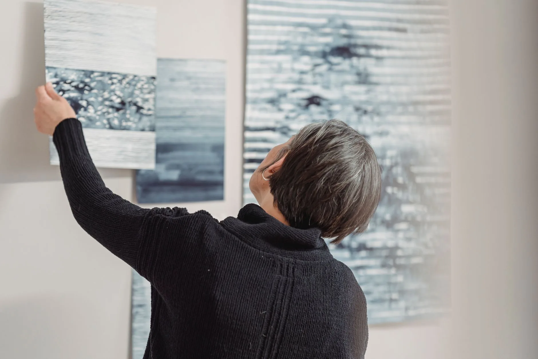 Visitor touches glowing, abstract art installation in dimly lit museum. Interactive art museums.